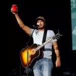 Luke Bryan on stage doing a cheers