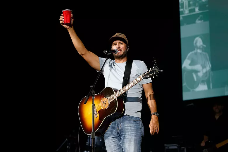 Luke Bryan on stage doing a cheers